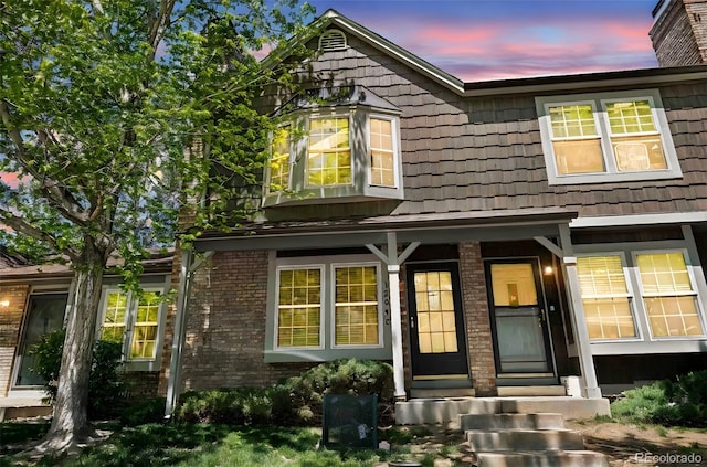 1209 S Flower Cir Unit C, Lakewood, CO 80232 - exterior entry at dusk featuring brick siding and covered porch