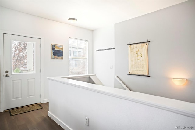 hall with baseboards, dark wood finished floors, and an upstairs landing