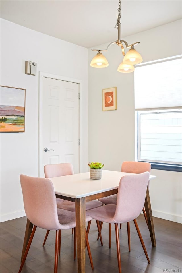 dining area with dark wood-style floors, a notable chandelier, and baseboards