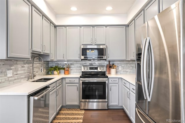 kitchen with dark wood finished floors, light countertops, stainless steel appliances, gray cabinetry, and a sink