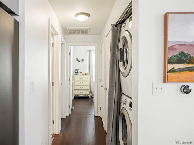 washroom featuring stacked washing maching and dryer, laundry area, visible vents, and dark wood-style flooring