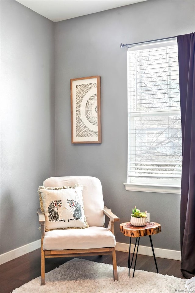 living area featuring baseboards, wood finished floors, and a healthy amount of sunlight