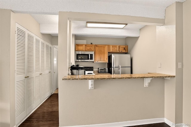 1365 Columbine St Unit 403, Denver, CO 80206 - kitchen with stainless steel appliances, dark wood-type flooring, a breakfast bar area, and a peninsula
