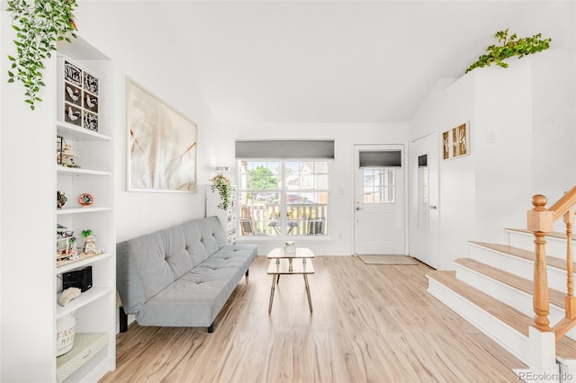 living area featuring stairs, vaulted ceiling, and wood finished floors