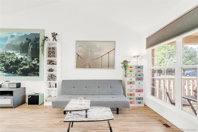 living area with visible vents, vaulted ceiling, and wood finished floors