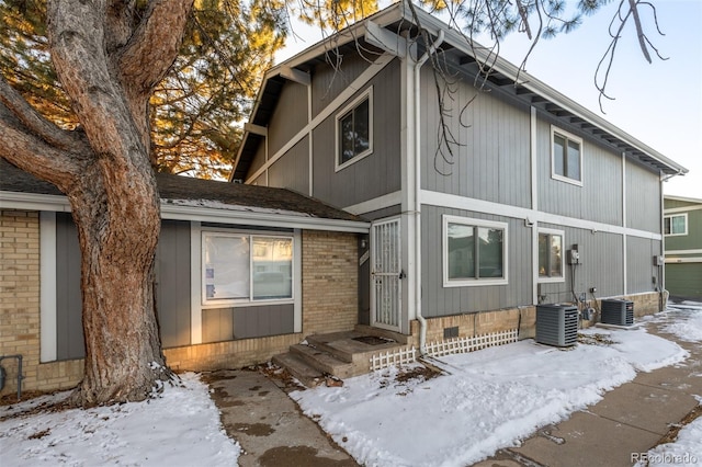 snow covered property featuring central AC unit