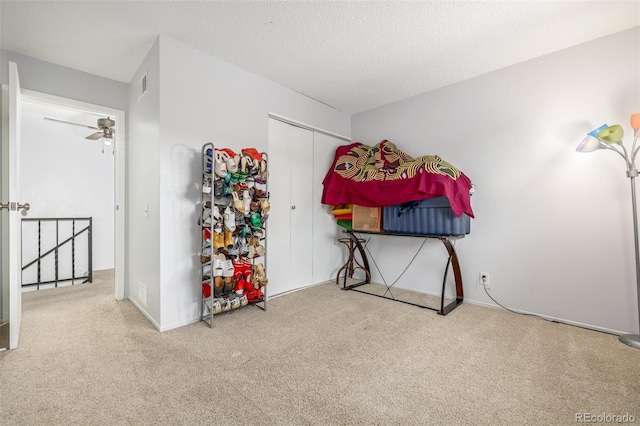 interior space with a textured ceiling, ceiling fan, and light carpet