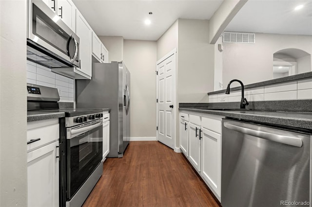 kitchen featuring white cabinets, dark wood-type flooring, stainless steel appliances, decorative backsplash, and sink