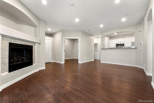 unfurnished living room with dark hardwood / wood-style floors and a tile fireplace