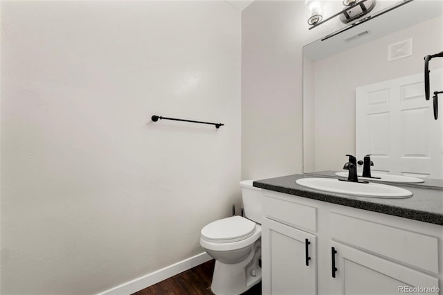 bathroom with toilet, vanity, and wood-type flooring