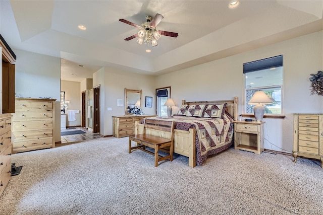 carpeted bedroom with a ceiling fan, baseboards, recessed lighting, a raised ceiling, and connected bathroom