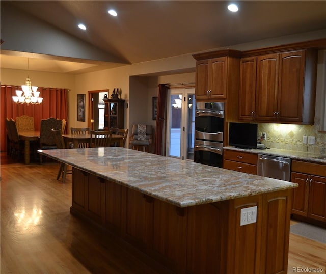 kitchen featuring light stone countertops, a kitchen island, a breakfast bar, light wood-style flooring, and appliances with stainless steel finishes