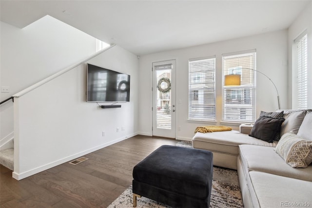 living room featuring visible vents, stairway, baseboards, and wood finished floors