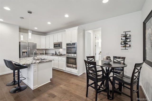 kitchen featuring a sink, light stone counters, white cabinetry, appliances with stainless steel finishes, and dark wood-style flooring