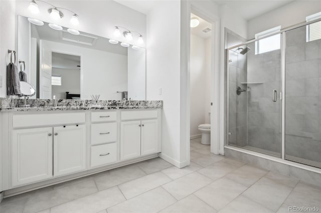 full bath with a sink, a shower stall, toilet, and double vanity