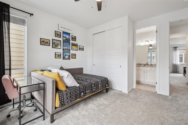 carpeted bedroom featuring ensuite bath, baseboards, a closet, and ceiling fan