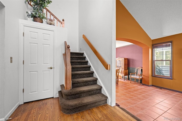 10519 Winterflower Way, Parker, CO 80134 - stairway with arched walkways, baseboards, high vaulted ceiling, and a textured ceiling