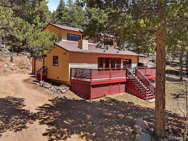 10852 Conifer Mountain Rd, Conifer, CO 80433 - rear view of house with a wooden deck, stairs, dirt driveway, and roof with shingles