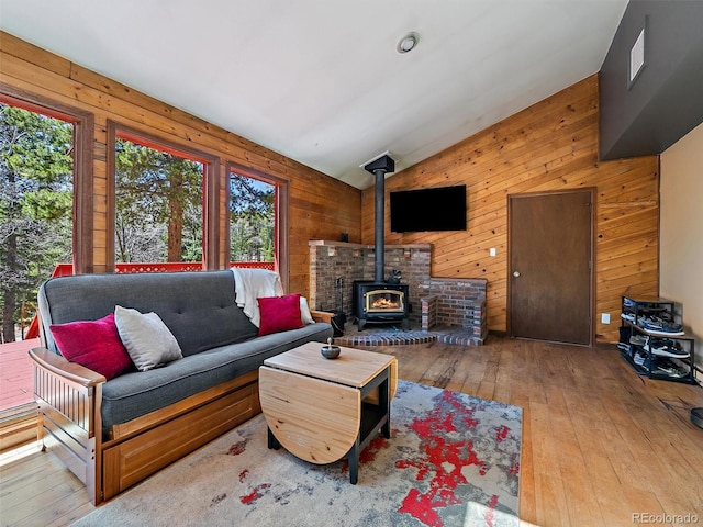 10852 Conifer Mountain Rd, Conifer, CO 80433 - living area with healthy amount of natural light, vaulted ceiling, a wood stove, hardwood / wood-style floors, and wood walls