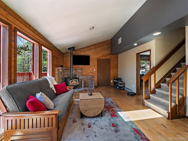 10852 Conifer Mountain Rd, Conifer, CO 80433 - living room featuring plenty of natural light, a wood stove, wood finished floors, wooden walls, and stairs