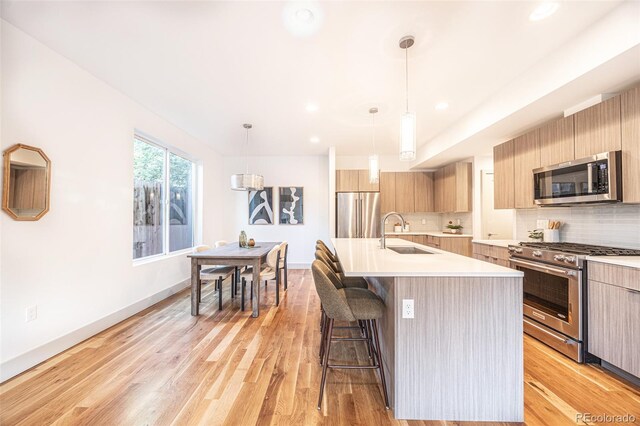 822 Fairfax St, Denver, CO 80220 - kitchen with appliances with stainless steel finishes, modern cabinets, a kitchen bar, light countertops, and recessed lighting