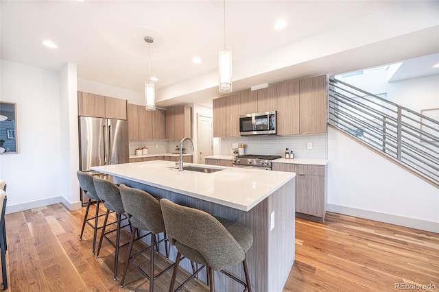 822 Fairfax St, Denver, CO 80220 - kitchen featuring high end appliances, modern cabinets, a kitchen breakfast bar, decorative backsplash, and light wood-style floors