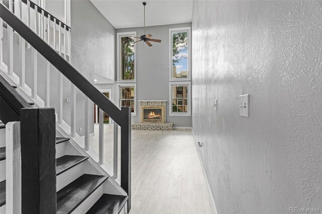 entryway with light hardwood / wood-style flooring, a brick fireplace, and ceiling fan