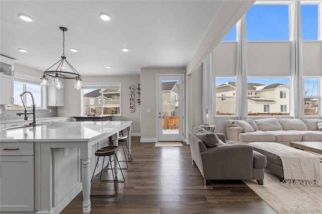 kitchen with a kitchen breakfast bar, white cabinets, decorative light fixtures, sink, and dark hardwood / wood-style floors