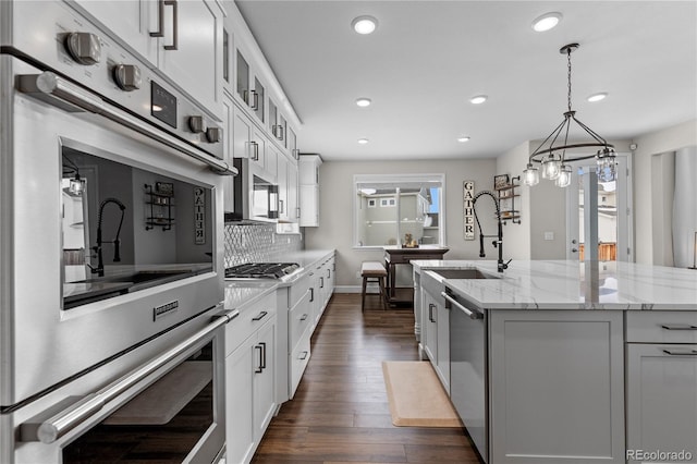 kitchen featuring white cabinets, a kitchen island with sink, pendant lighting, and stainless steel appliances