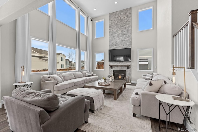 living room with hardwood / wood-style flooring, a high ceiling, and a stone fireplace