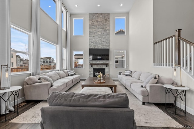 living room with a fireplace, a towering ceiling, and dark hardwood / wood-style flooring