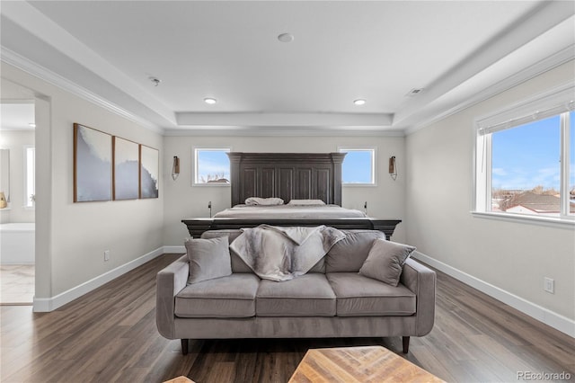 bedroom featuring dark wood-type flooring, connected bathroom, a tray ceiling, and crown molding