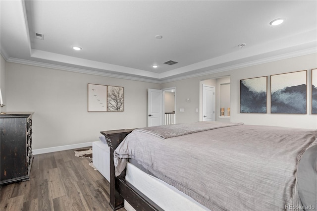 bedroom featuring crown molding, hardwood / wood-style flooring, and a tray ceiling