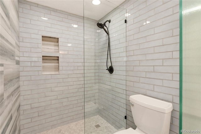 bathroom featuring a tile shower and toilet