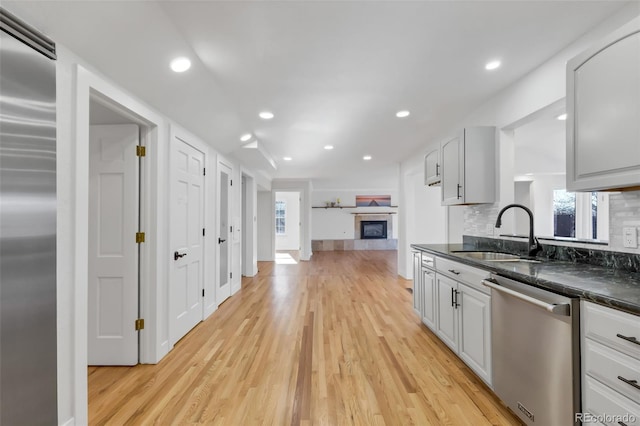 kitchen with white cabinetry, sink, light hardwood / wood-style floors, decorative backsplash, and appliances with stainless steel finishes