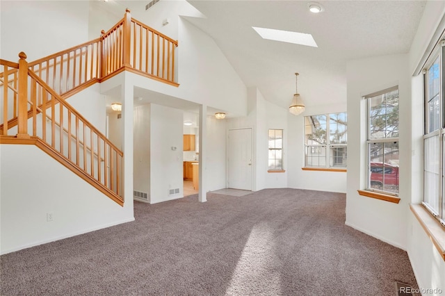 unfurnished living room with a skylight, visible vents, stairway, carpet flooring, and high vaulted ceiling