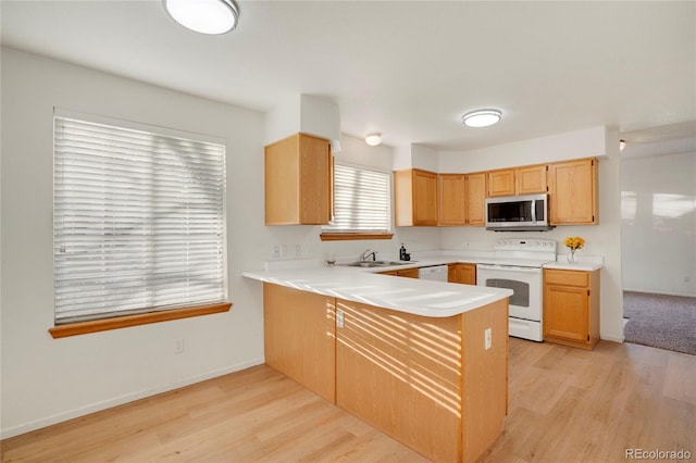 kitchen featuring light countertops, white appliances, light wood-type flooring, and a peninsula