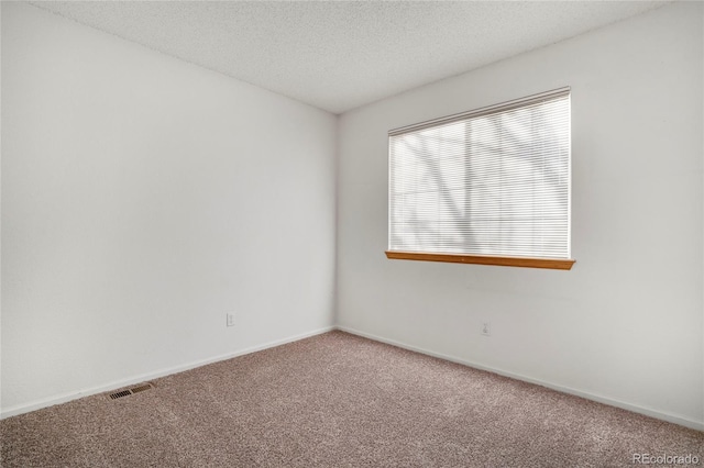 carpeted spare room with visible vents, a textured ceiling, and baseboards