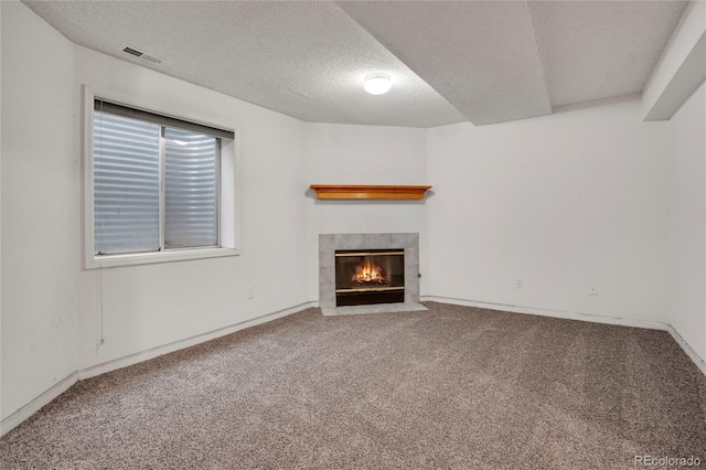 unfurnished living room with carpet, a fireplace, visible vents, and a textured ceiling