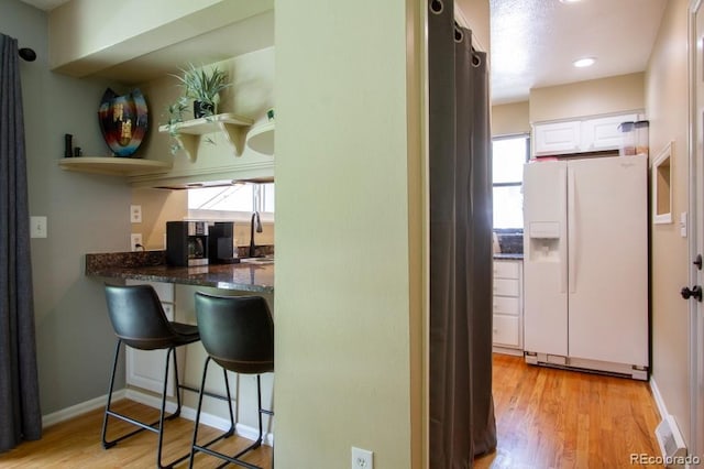 10652 W Florida Ave Unit D, Lakewood, CO 80232 - kitchen with white fridge with ice dispenser, white cabinets, plenty of natural light, and light wood-style floors