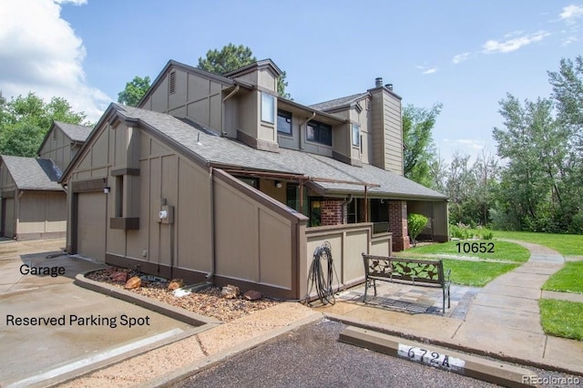 10652 W Florida Ave Unit D, Lakewood, CO 80232 - view of front of home featuring a chimney, roof with shingles, a front lawn, and a garage
