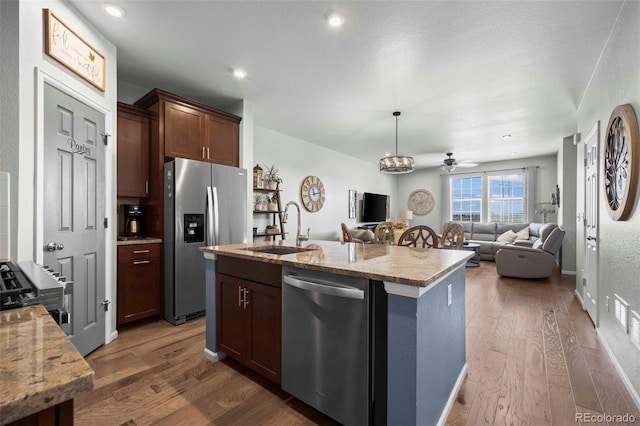 119 Jackson Dr, Erie, CO 80516 - kitchen with a kitchen island with sink, a sink, wood finished floors, light stone counters, and appliances with stainless steel finishes