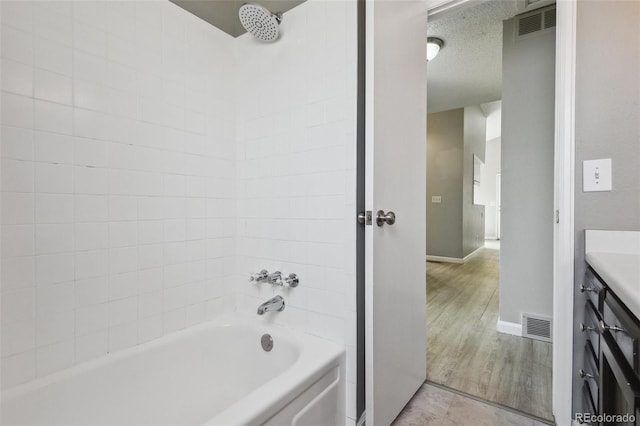 full bath with tub / shower combination, wood finished floors, visible vents, baseboards, and vanity
