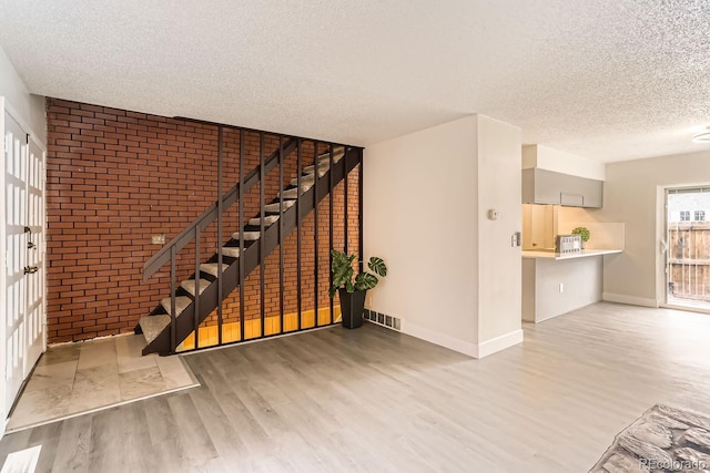 unfurnished living room with a textured ceiling and light hardwood / wood-style floors