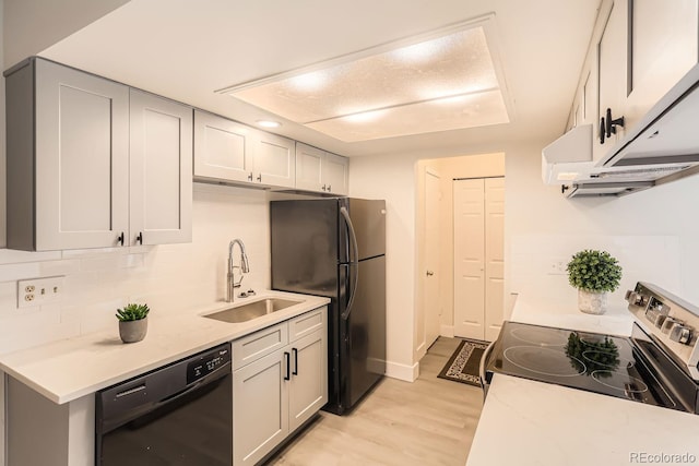 kitchen with light stone countertops, light wood-type flooring, sink, black appliances, and gray cabinets