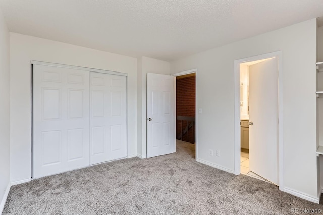 unfurnished bedroom featuring a textured ceiling, light carpet, and a closet