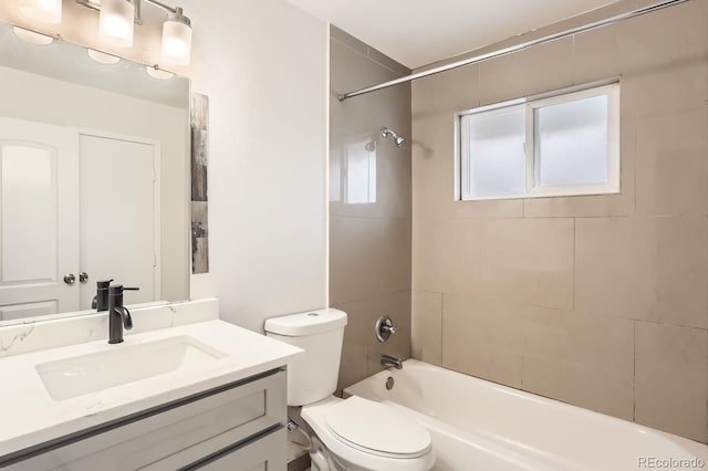 full bathroom featuring tiled shower / bath combo, toilet, and vanity