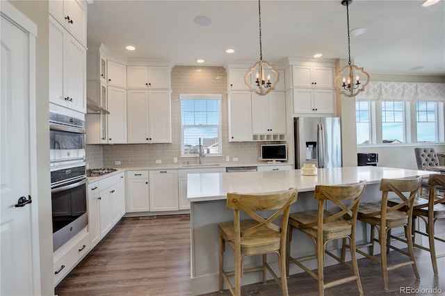 kitchen featuring stainless steel appliances, light countertops, a kitchen island, and tasteful backsplash