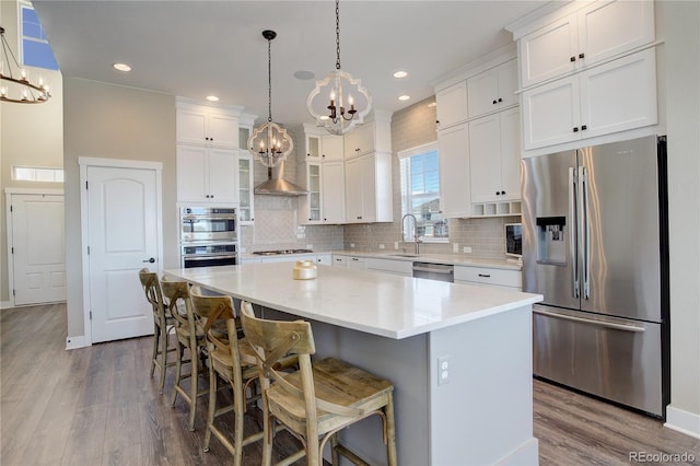 kitchen with stainless steel appliances, white cabinets, a notable chandelier, and a kitchen island