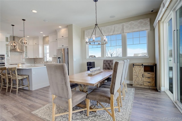 dining area featuring light wood-type flooring, a notable chandelier, baseboards, and recessed lighting